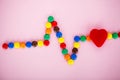 Colored Candy in the Form of Cardiogram on the Pink Background.
