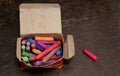 Colored chalks on box with blackboard