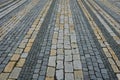 Colored cobblestone cube tiles of gray brown and black color laid in rows on the square. It creates the impression of giant mosaic