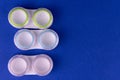 Colored containers for contact lenses for eyes on a blue background. Copy space. Royalty Free Stock Photo