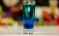 Colored drink in glass for shots, a combination of green with bl