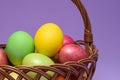 Colored easter eggs in a basket on a purple background