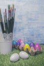 Colored Easter eggs in egg on grass with paint brushes Royalty Free Stock Photo