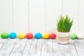 Colored easter eggs, flower pot with green grass on wooden background. Space for text. Selective focus. Royalty Free Stock Photo