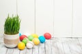 Colored easter eggs, flower pot with green grass on wooden background. Space for text. Selective focus. Royalty Free Stock Photo