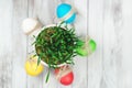 Colored easter eggs, flower pot with green grass on wooden background. Top view. Royalty Free Stock Photo