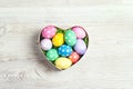 Colored Easter eggs in heart shaped box on light wooden background Royalty Free Stock Photo