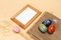 Colored Easter eggs on a sackcloth bag and a photo frame.