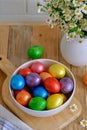 Colored Easter eggs with wild chamomy on old wood table on brick wall background Royalty Free Stock Photo