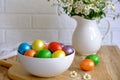 Colored Easter eggs with wild chamomy on old wood table on brick wall background Royalty Free Stock Photo