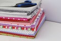 Colored fabric folded stack with scissors on the gray background