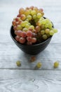 Colored grapes in a black bowl on a gray wooden table,top view and copy space Royalty Free Stock Photo