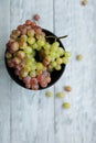 Colored grapes in a black bowl on a gray wooden table.Top view Royalty Free Stock Photo