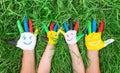 Colored hands with smile painted in colorful paints against green summer background. Lifestyle concept Royalty Free Stock Photo
