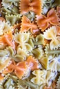 Colored italian cooked pasta farfalle tricolore abstract backdrop.