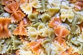 Colored italian cooked pasta farfalle tricolore abstract background.