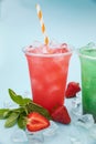 Colored lemonades in plastic cups with ice, fruits and berries