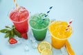 Colored lemonades in plastic cups with ice, fruits and berries