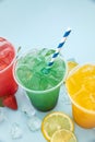 Colored lemonades in plastic cups with ice, fruits and berries