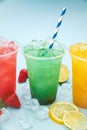 Colored lemonades in plastic cups with ice, fruits and berries