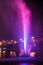 Colored luminous fountain in the middle of the lake at night.