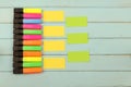 Colored markers and pieces of paper for notes lie on a wooden background.