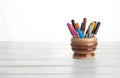 Colored markers stand in a clay pot, isolated on a white wooden background. Royalty Free Stock Photo