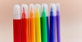 Colored markers thin thick red yellow green pink blue purple light background.