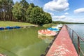 Colored old vintage plastic catamarans and boats near a wooden pier on the shore of a large lake Royalty Free Stock Photo