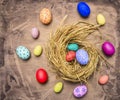 Colored ornamental eggs for Easter with painted faces lie in a nest wooden rustic background top view close up