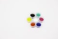 Colored paints in plastic jars in a circle on a white background. Free space for text. The view from the top Royalty Free Stock Photo