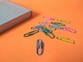 Colored paper clips on orange background