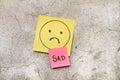 Colored paper notes with sad drawing face and single word on a gray marble background Royalty Free Stock Photo