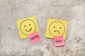 Colored paper notes with sad and happy drawing faces and single words on a gray marble background Royalty Free Stock Photo