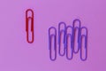 Colored paper red clip outstanding on purple background. minimal