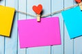 Colored paper sheets on thread with heart shaped clothespin blue wooden background Royalty Free Stock Photo