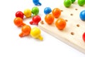 Colored pegs board, wood beads on white background