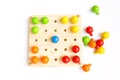 Colored pegs board, wood beads on white background