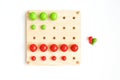 Colored pegs board, wood beads on white background