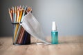 colored pencil in a black jar and mask placed on a wooden table