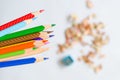Colored pencils against blurred shavings on white background. Royalty Free Stock Photo