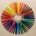 Colored pencils arranged in a circular pattern on a light wooden Royalty Free Stock Photo