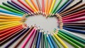 Colored pencils arranged radially on a white surface form a circular pattern with tips pointing Royalty Free Stock Photo