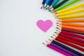 Colored pencils arranged in semi circle with heart on white background Royalty Free Stock Photo