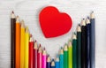 Colored Pencils and Big Red Heart on White Wood Background