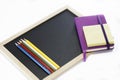 Colored pencils, black board, notebook and memopad Royalty Free Stock Photo