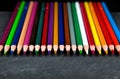 Colored pencils on a black stone slate Royalty Free Stock Photo