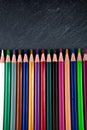 Colored pencils on a black stone slate Royalty Free Stock Photo