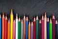 Colored pencils on a black stone slate Royalty Free Stock Photo