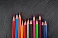 Colored pencils on a black stone slate Royalty Free Stock Photo